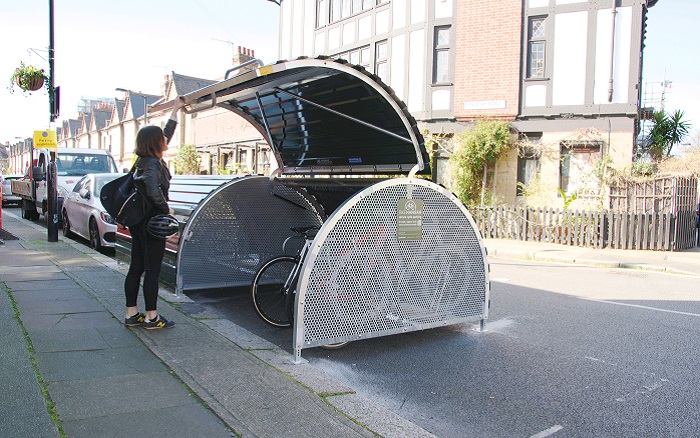 Woman putting her bike into a Cyclehangar on a residential street.